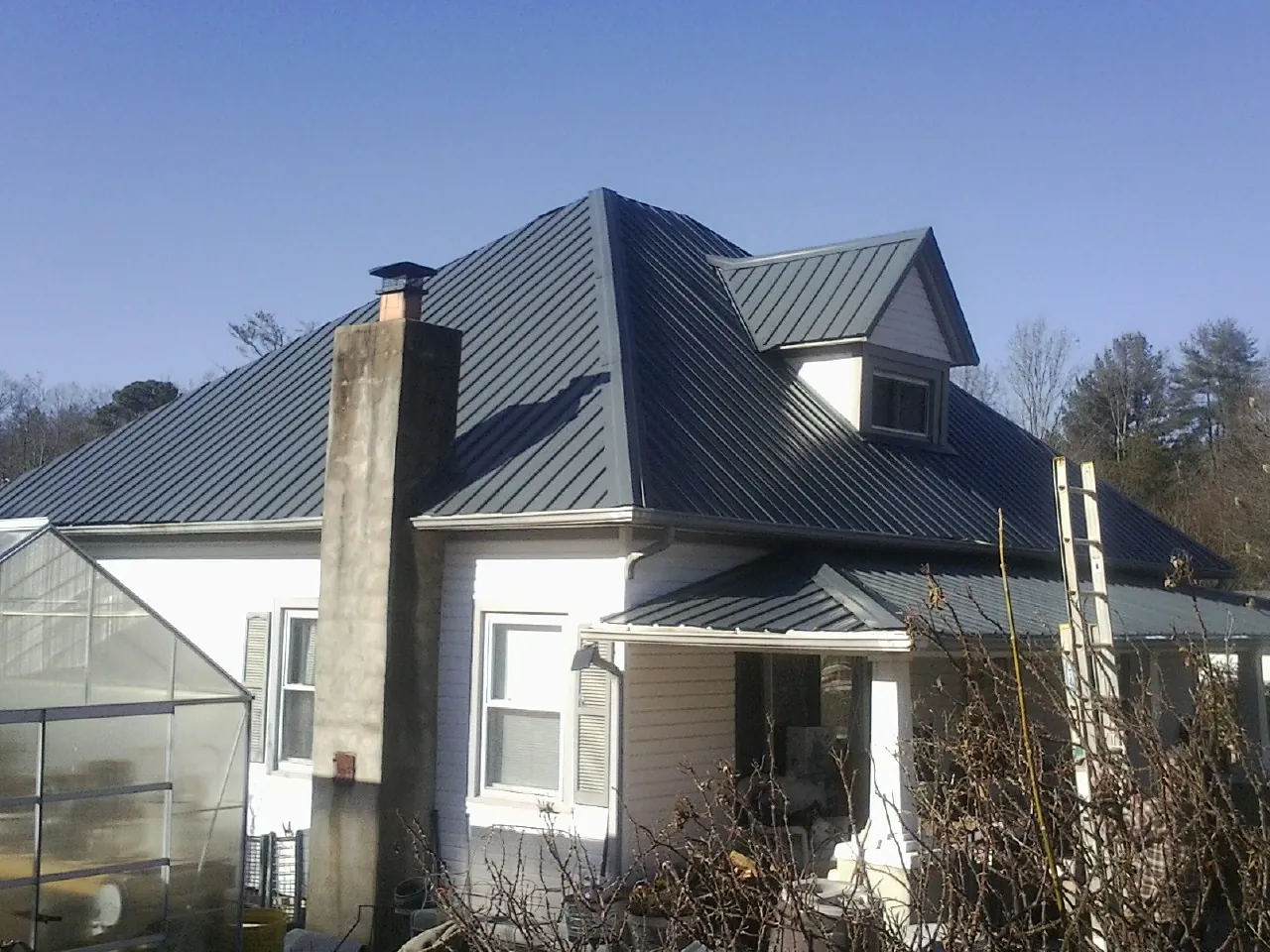 Dark blue standing seam metal roof on a white farmhouse with dormer — Slate & Tile Roof Repair by Roofing Brothers in Lore City