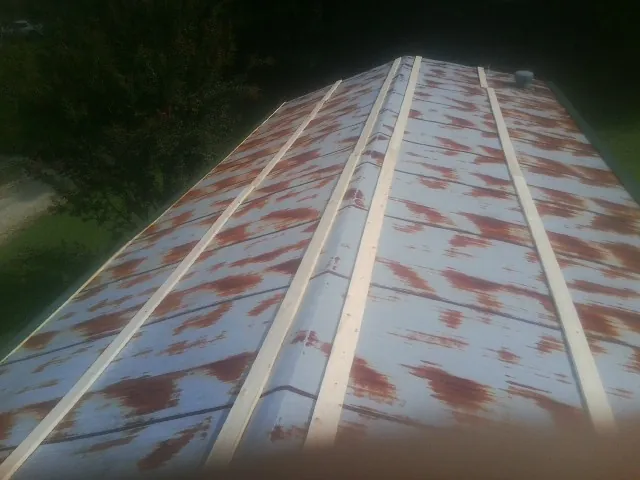 Rusted metal roof panels with new wood purlins before replacement — Storm Damage Roof Repair in Lore City by Roofing Brothers