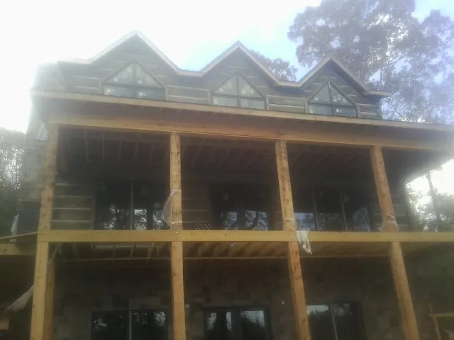 Dormers and porch framing on a large log home under construction — Roof Coating work by our crew in Lore City
