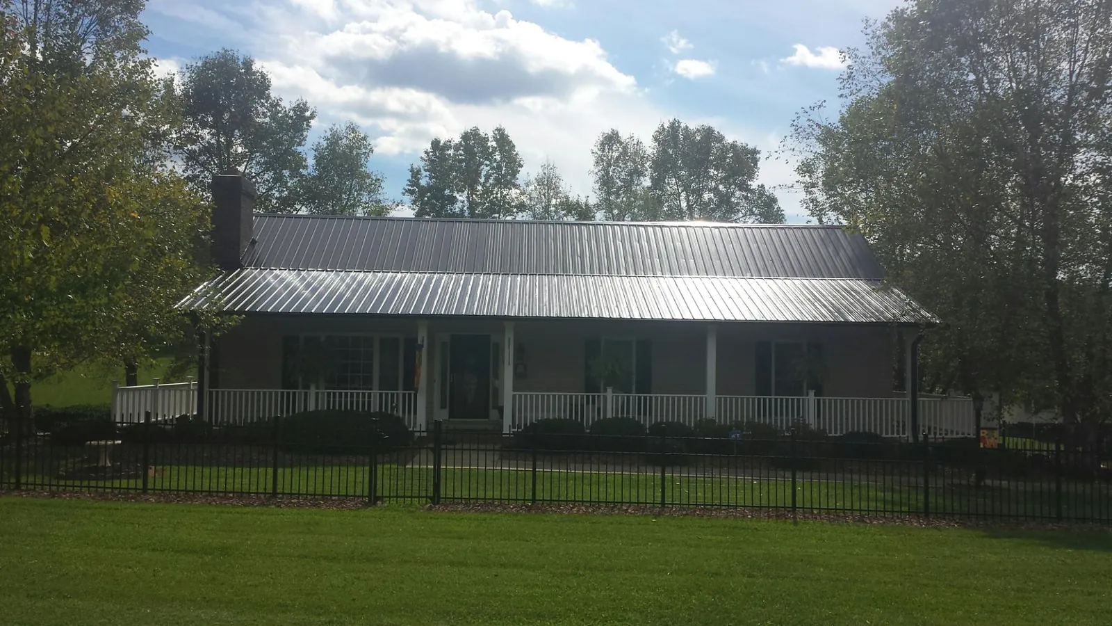 Gray metal roof on a brick ranch with a full width front porch — Gutter Guard Installation work by our crew in Lore City