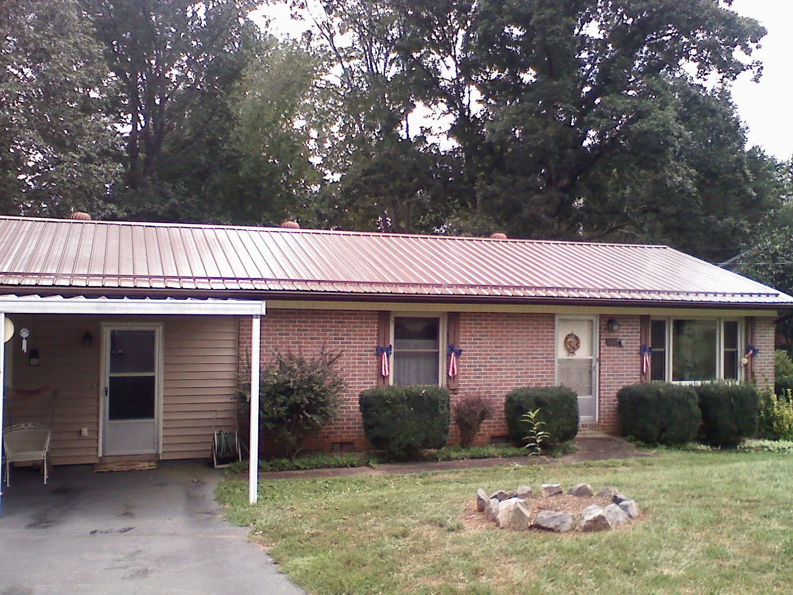 Bronze metal roof and carport on a brick ranch home — Roof Repair work by our crew in Lore City