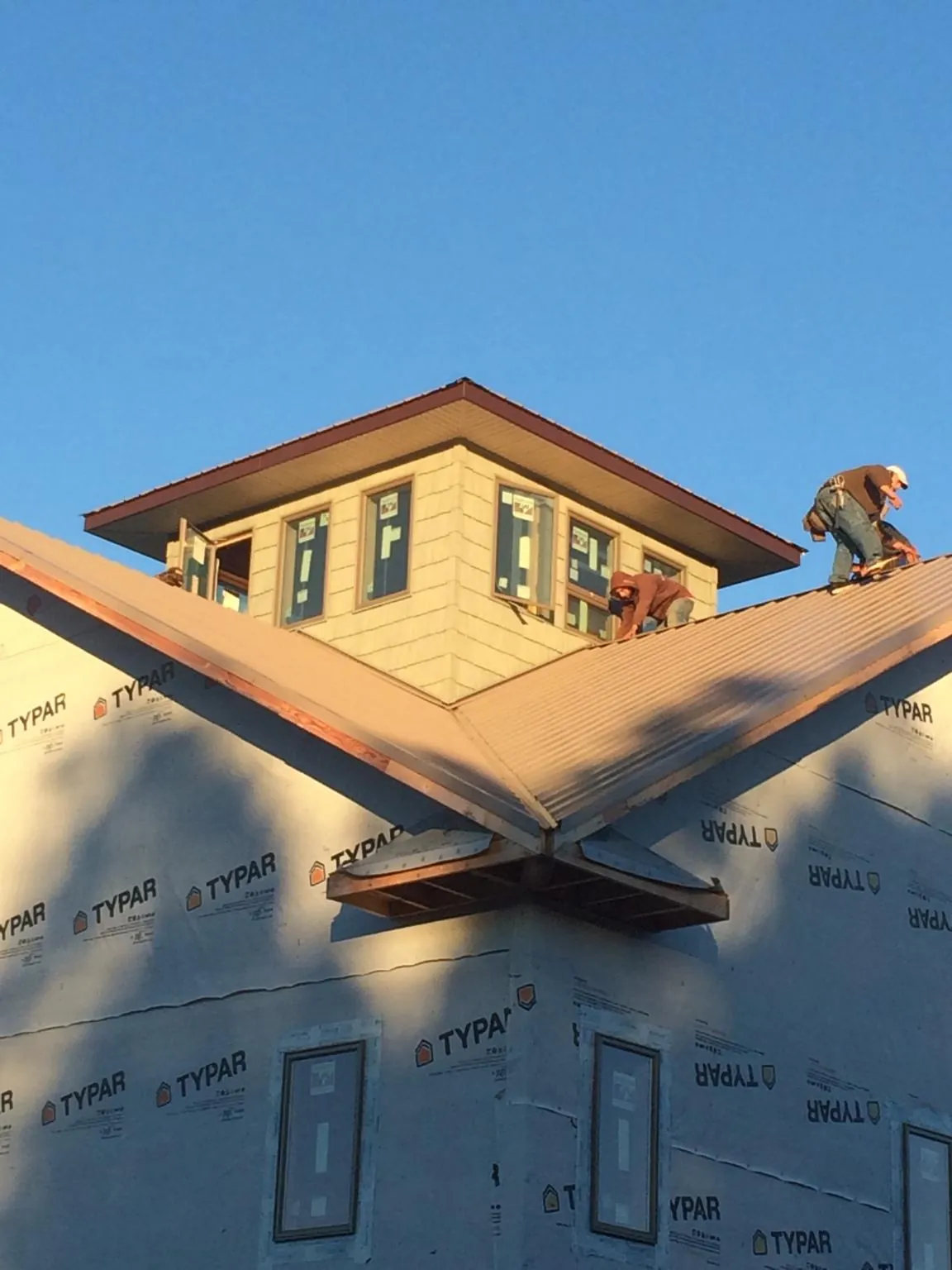 Roofers working around a rooftop cupola on a new metal roof at sunset — Roof Waterproofing in Lore City by Roofing Brothers